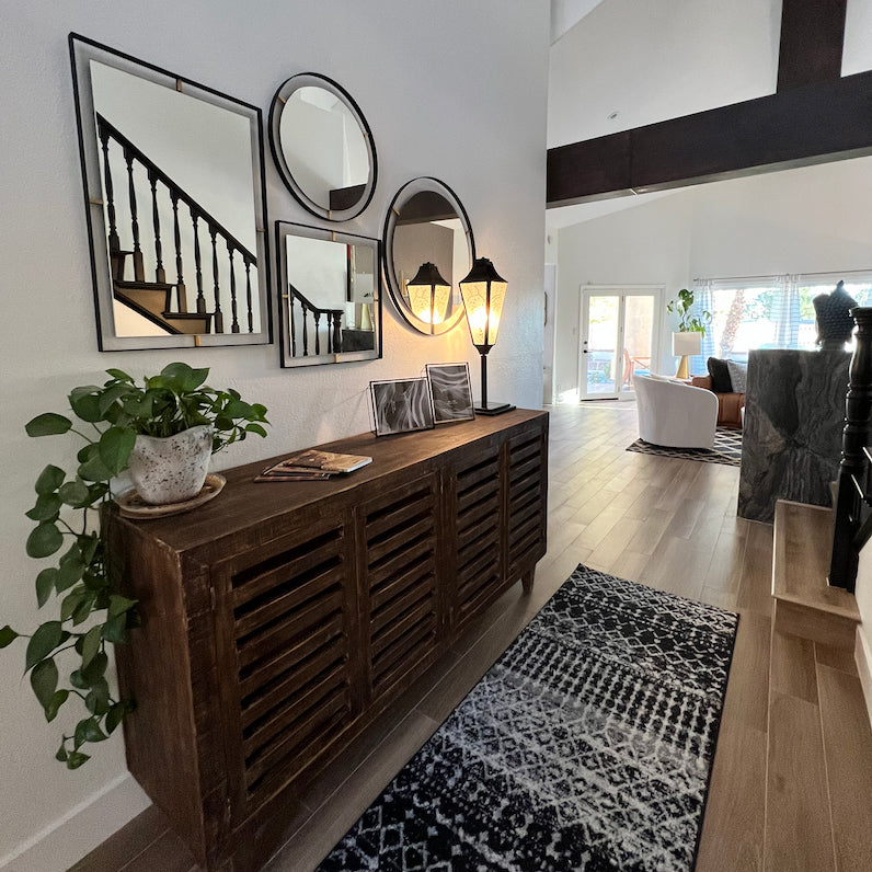 A brown wood table in a large home with multiple Varaluz mirrors and a table lamp