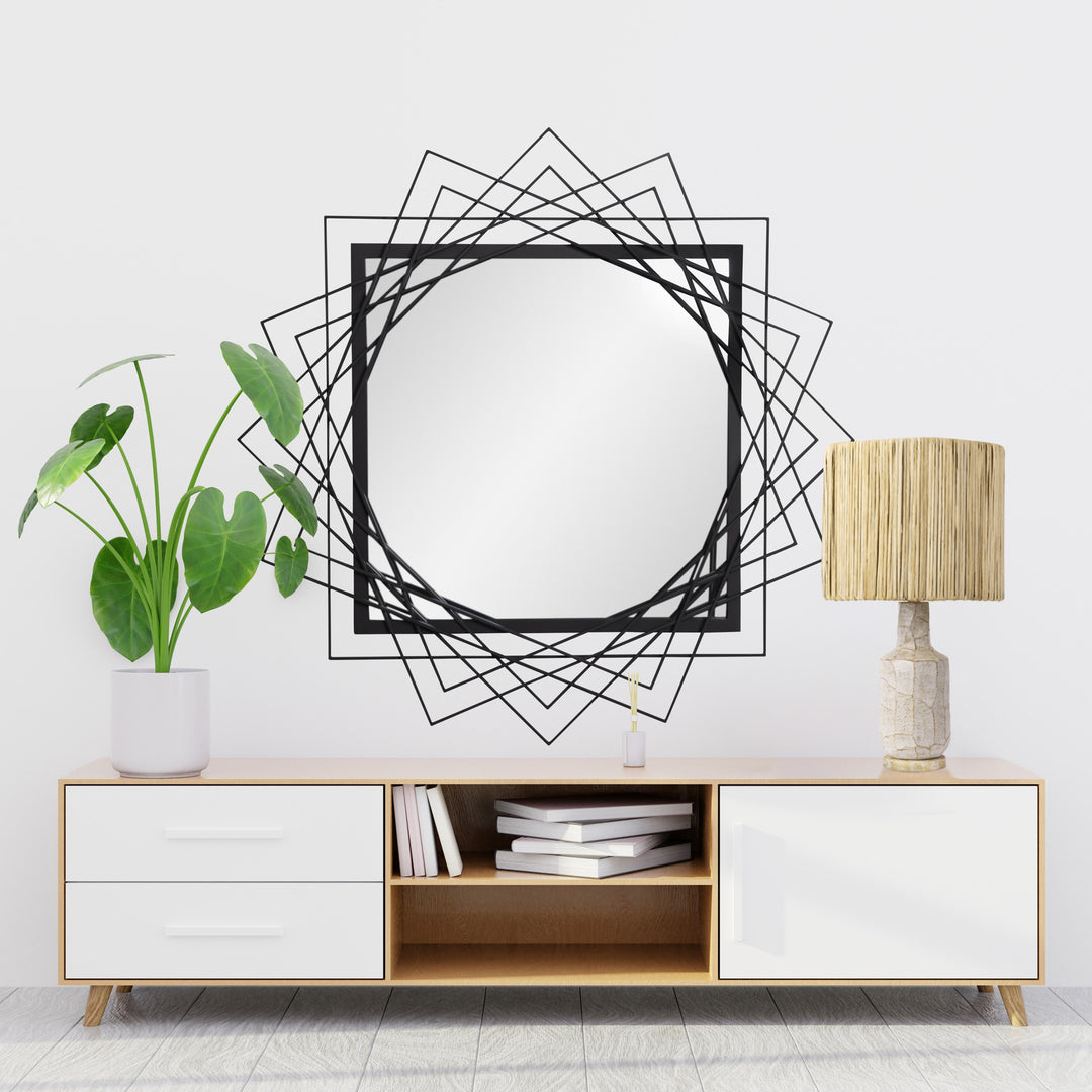 black square geometric wall mirror over a low console with a ceramic table lamp