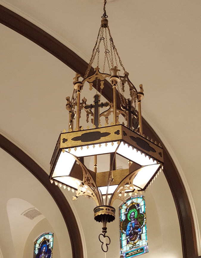 Chandelier hanging from a ceiling with stained glass windows in the background