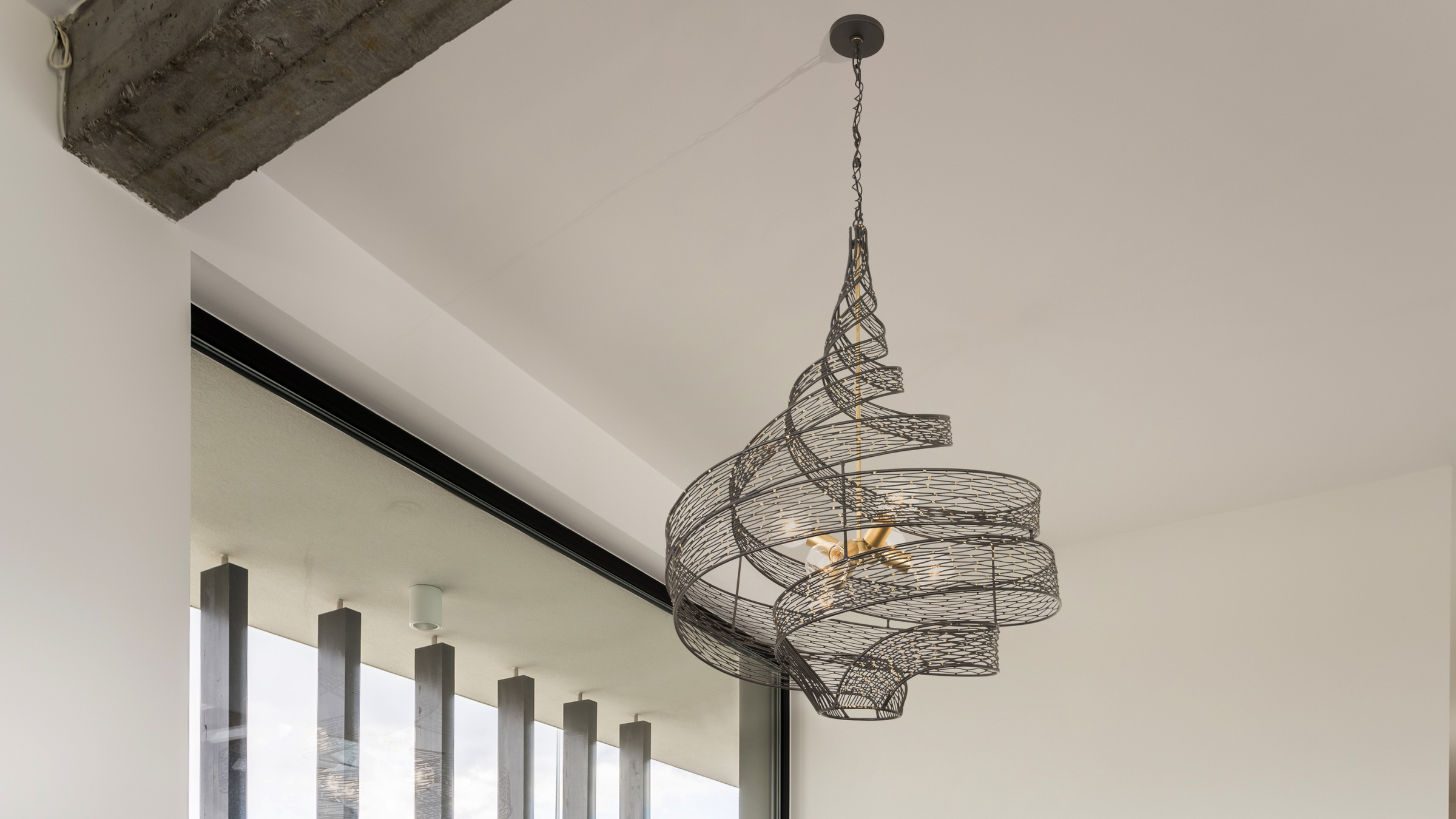 Flow twist pendant shown hung on ceiling next to wooden beam