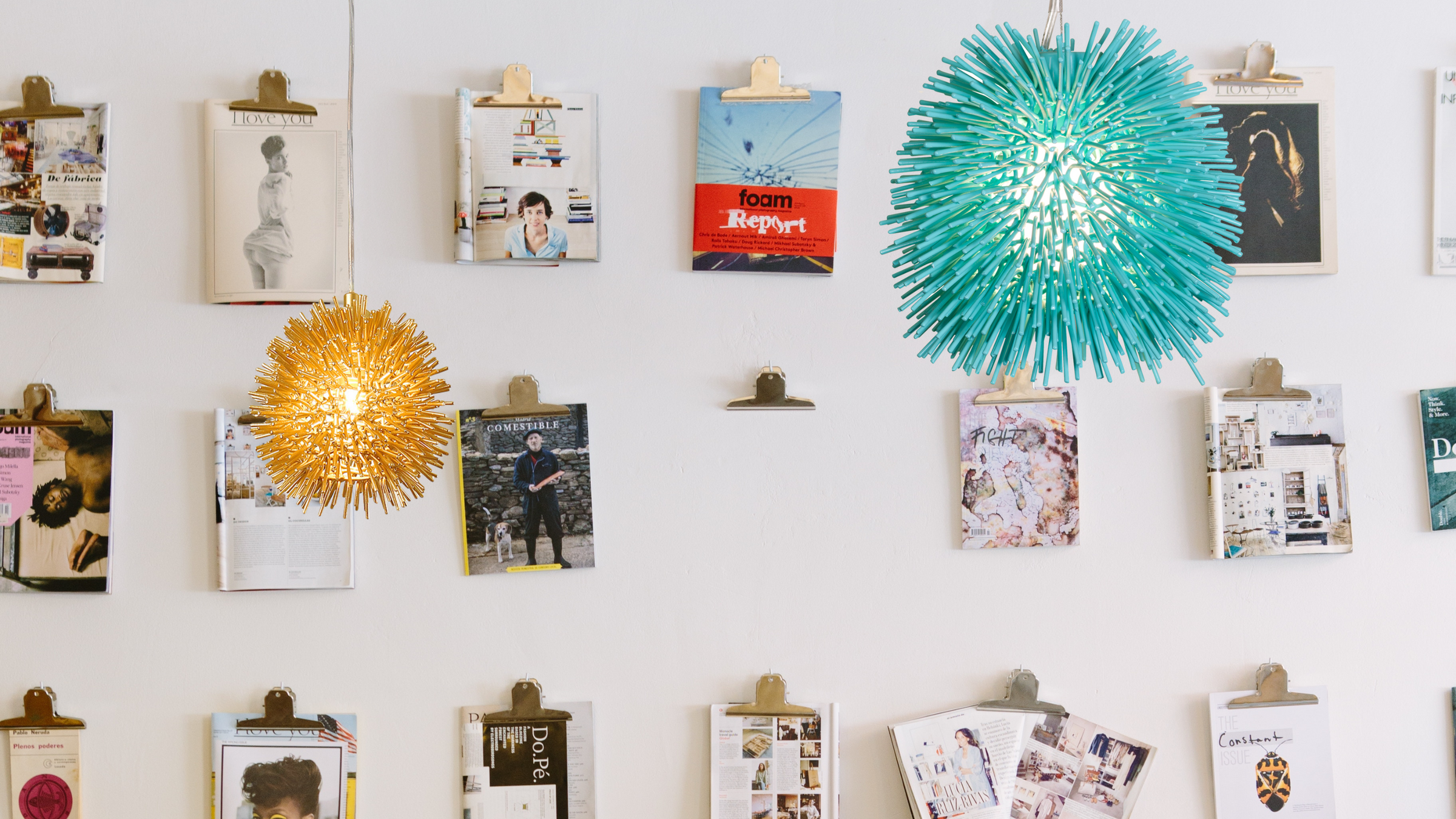 Colorful urchin pendants shown next to a wall hung with various publications and drawings